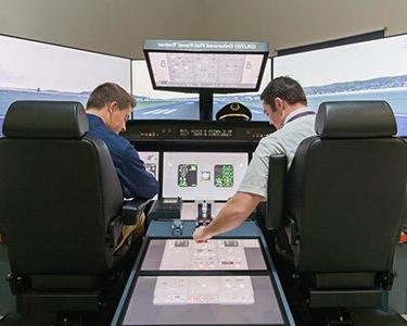 Two 密歇根州立大学丹佛 students operating a flight simulator on Auraria Campus.